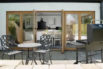 a patio with a grill and a table and chairs at 4-Bed Cottage - Pets with Garden & Wood Burner in Helston