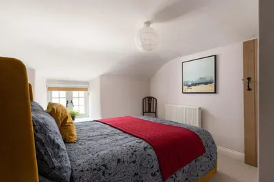 a bedroom with a bed with a red blanket at 4-Bed Cottage - Pets with Garden & Wood Burner in Helston