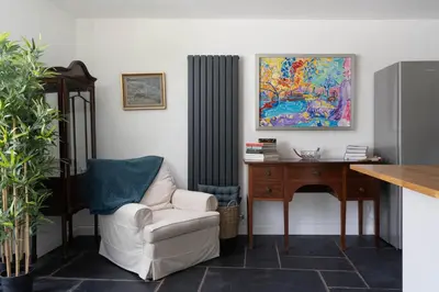 a living room with a chair and a desk at 4-Bed Cottage - Pets with Garden & Wood Burner in Helston