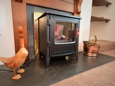 a wood stove in a living room with a chair at 4 Bed in St. Austell oc-82414 in Saint Stephen