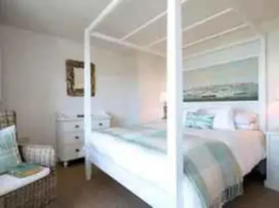 a bedroom with a large white bed and a chair at Castaway, Port Isaac Bay Holidays in Port Isaac