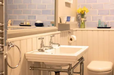 a bathroom with a sink and a toilet and a mirror at Rosemary Cottage, Port Isaac Bay Holidays in Port Isaac