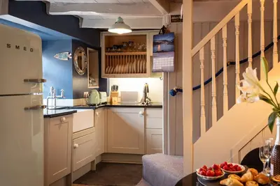 a kitchen with white cabinets and a staircase at Rosemary Cottage, Port Isaac Bay Holidays in Port Isaac