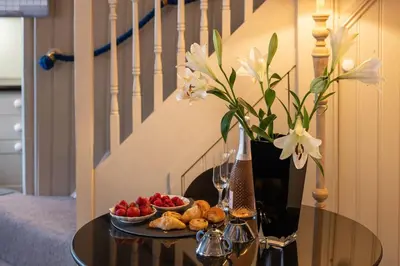 a table with a bowl of fruit and a vase with flowers at Rosemary Cottage, Port Isaac Bay Holidays in Port Isaac