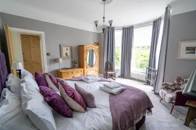 a bedroom with a large bed with purple pillows at Stunning 4 bedroom house in Wadebridge, Cornwall - 2 living rooms and superking beds in Wadebridge
