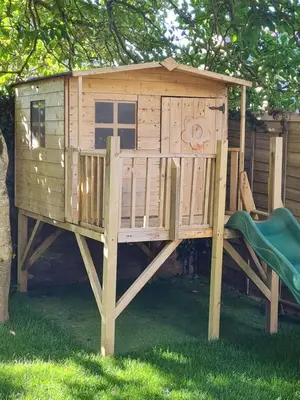 a wooden play house with a slide in the grass at Stunning 4 bedroom house in Wadebridge, Cornwall - 2 living rooms and superking beds in Wadebridge