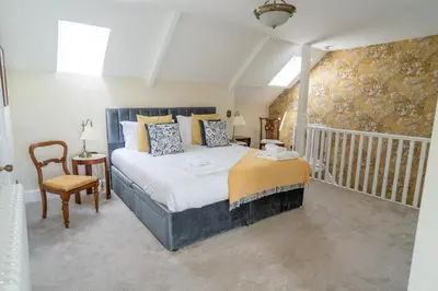 a bedroom with a large bed and a chair at Stunning 4 bedroom house in Wadebridge, Cornwall - 2 living rooms and superking beds in Wadebridge