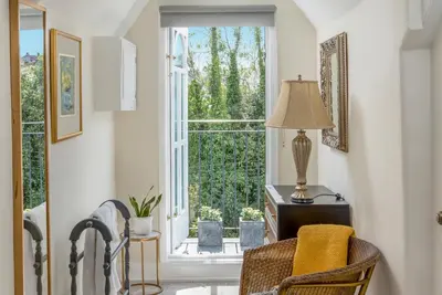 a room with a window and a chair and a lamp at Stunning 4 bedroom house in Wadebridge, Cornwall - 2 living rooms and superking beds in Wadebridge
