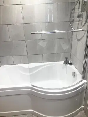 a white bath tub with a shower and a sink at Apartment in lovely village in Newquay
