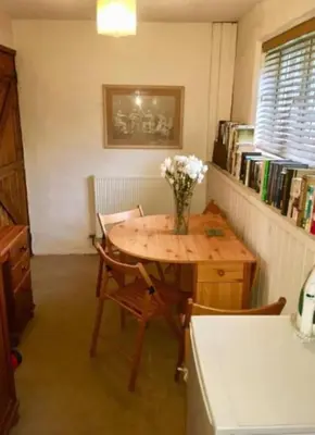 a room with a table with a vase of flowers on it at Apartment in lovely village in Newquay