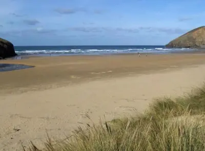 a beach with people walking on the sand at Apartment in lovely village in Newquay
