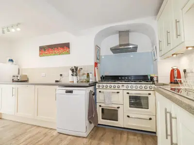 a kitchen with white cabinets and a stove top oven at Langurra in Newquay