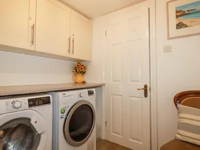 a laundry room with a washer and dryer at Langurra in Newquay