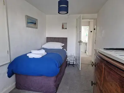 a bedroom with a blue bed with towels on it at Langurra in Newquay