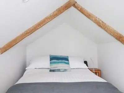 a bedroom with a bed in a white room at Langurra in Newquay