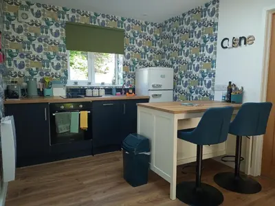 a kitchen with blue cabinets and a counter with blue chairs at Hygga in Fowey