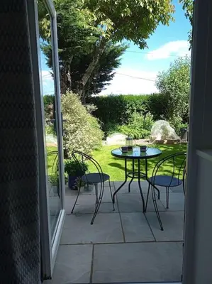 an open door to a patio with a table and chairs at Hygga in Fowey