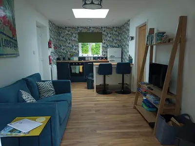 a living room with a blue couch and a kitchen at Hygga in Fowey