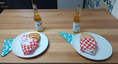two bottles of beer and two sandwiches on a table at Hygga in Fowey