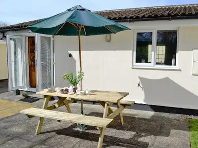 a picnic table with an umbrella and a bench at Stone The Crows in Liskeard