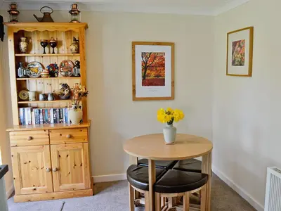 a dining room with a table and a cabinet at Stone The Crows in Liskeard