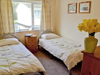 two beds in a room with a vase of flowers at Stone The Crows in Liskeard