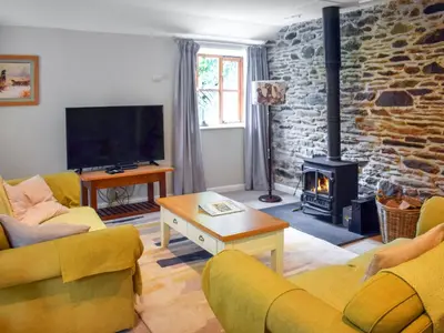 a living room with a fireplace and a stone wall at Grain Store 1 - 29635 in Portloe