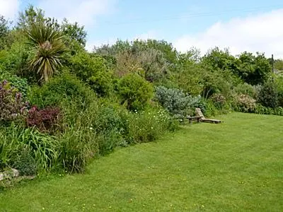 a park with a bench in the middle of a field at Grain Store 1 - 29635 in Portloe