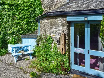 a blue bench sitting outside of a stone cottage at Grain Store 1 - 29635 in Portloe
