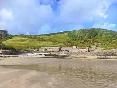 a view of a beach with houses and a hill at Grain Store 2 - 29636 in Portloe