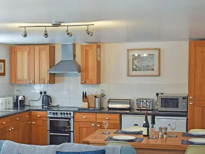 a kitchen with wooden cabinets and a stove top oven at Grain Store 2 - 29636 in Portloe
