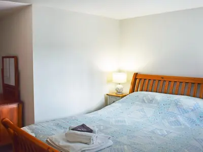 a bedroom with a bed with a blue comforter at Grain Store 2 - 29636 in Portloe