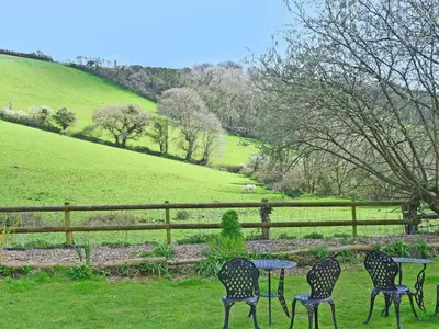 four chairs and a table in front of a fence at Grain Store 2 - 29636 in Portloe