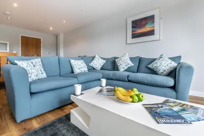 a blue couch in a living room with a table at The Glades - Retallack in Saint Columb Major