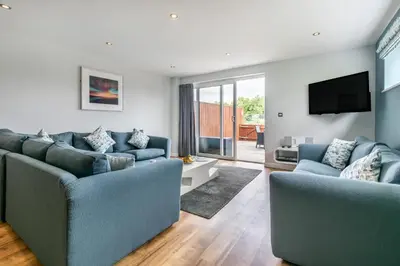 a living room with two blue couches and a tv at The Glades - Retallack in Saint Columb Major