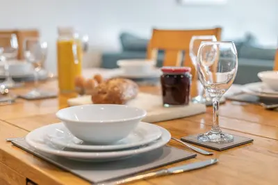 a wooden table with a plate and a bowl and a glass at The Glades - Retallack in Saint Columb Major