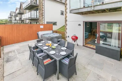 a patio with a table and chairs and a grill at The Glades - Retallack in Saint Columb Major