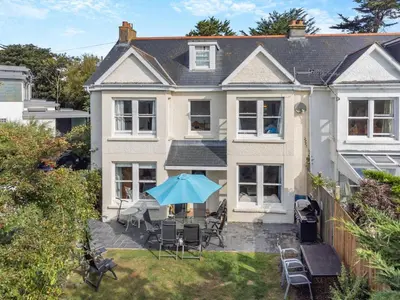 a house with a patio with a blue umbrella at 5 Bed in Trebetherick oc-b29371 in Polzeath
