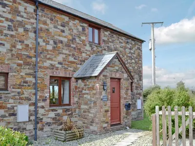 a brick house with a red door and a fence at Harvest Cottage in Padstow