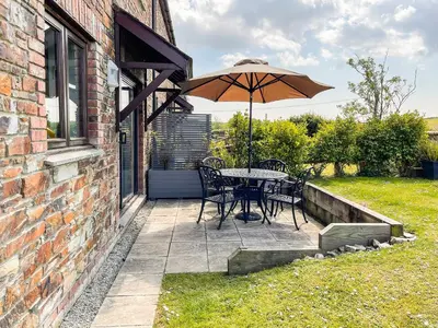 a table and chairs with an umbrella on a patio at Harvest Cottage in Padstow