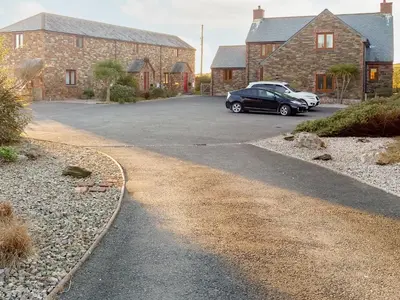 a driveway with two cars parked in front of a house at Harvest Cottage in Padstow