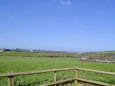a wooden fence in front of a green field at Harvest Cottage in Padstow