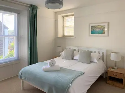 a bedroom with a white bed with a towel on it at Hillside in Port Isaac