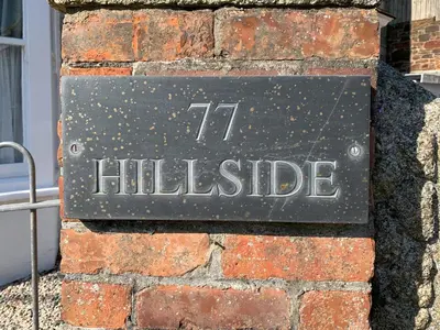 a sign on the side of a brick wall at Hillside in Port Isaac