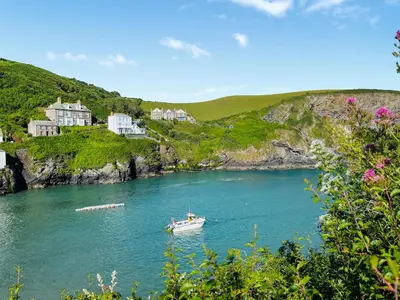 a boat in a body of water with houses at Hillside in Port Isaac