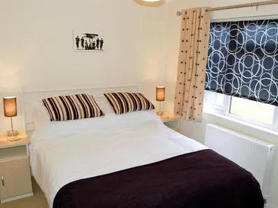 a bedroom with a white bed with two lamps and a window at Rosewater Lodge in Saint Teath
