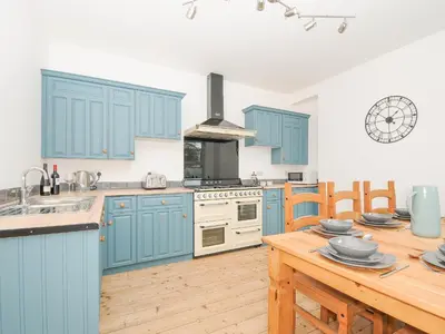a kitchen with blue cabinets and a wooden table at Albert House in Looe