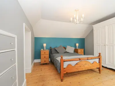 a bedroom with a bed with blue walls and a chandelier at Albert House in Looe