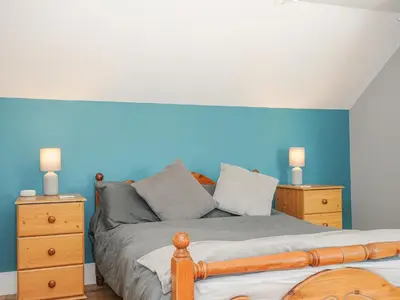 a bedroom with a bed with a blue wall at Albert House in Looe