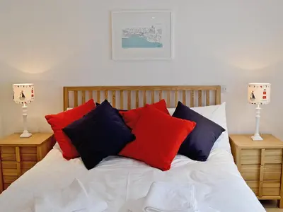 a bed with red and blue pillows on it at Sea Vista in Port Isaac